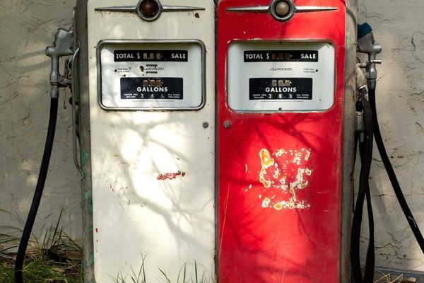 A pair of old gas pumps—one white, one red—juxtaposed side-by-side