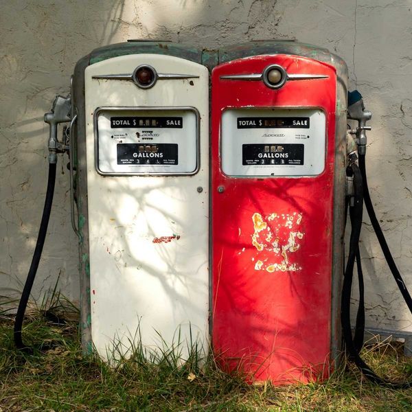 A pair of old gas pumps—one white, one red—juxtaposed side-by-side