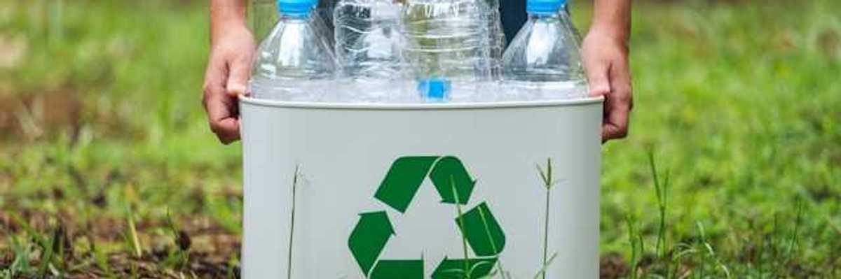 A person collecting plastic bottles in a recycling container