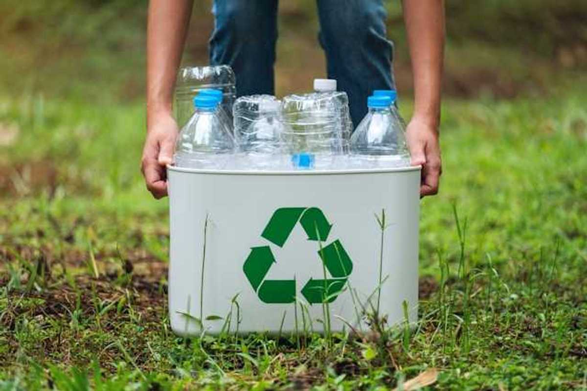 A person collecting plastic bottles in a recycling container