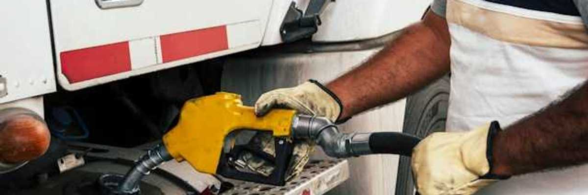 A person fueling a large truck with a yellow nozzle