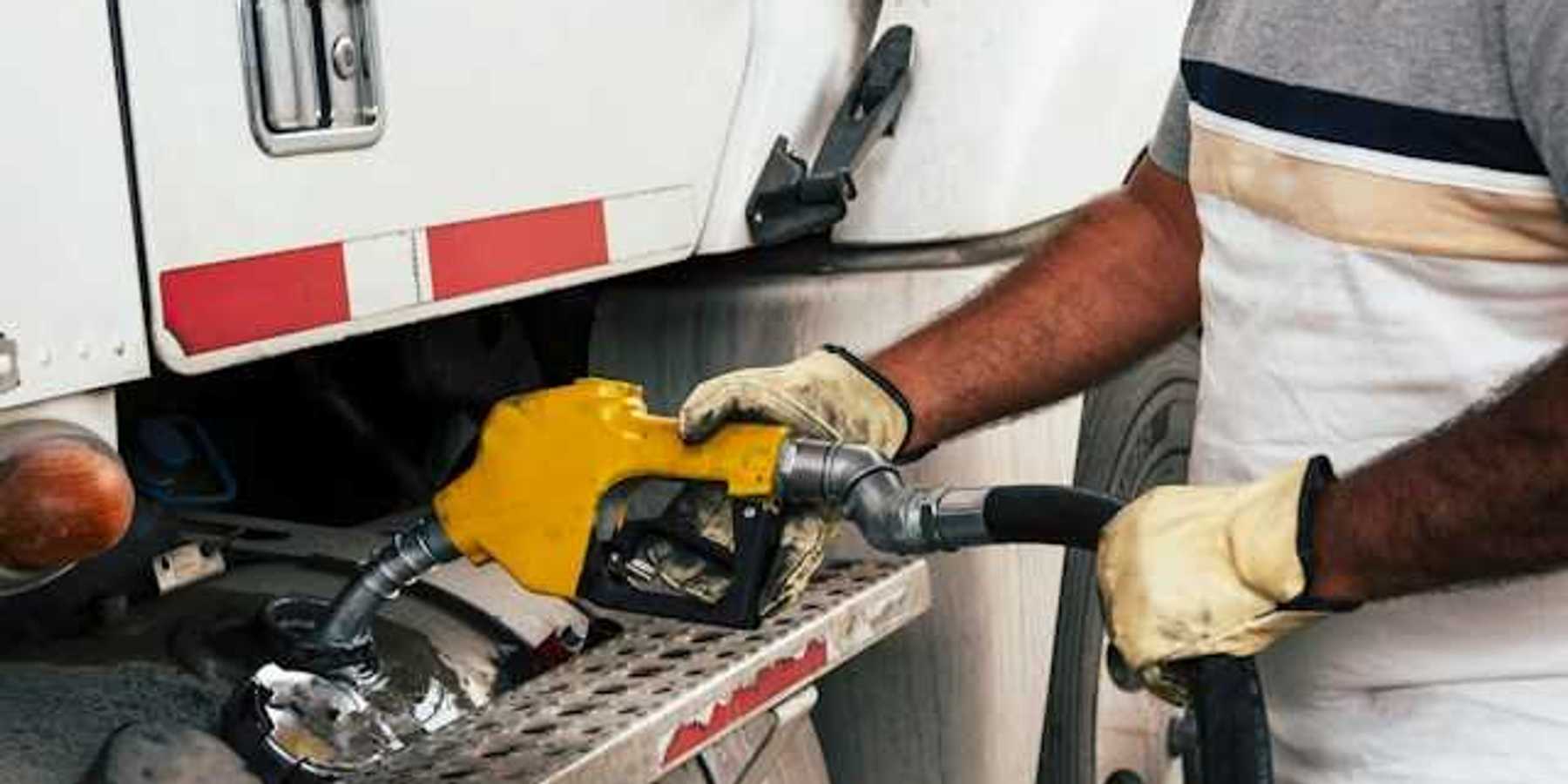 A person fueling a large truck with a yellow nozzle