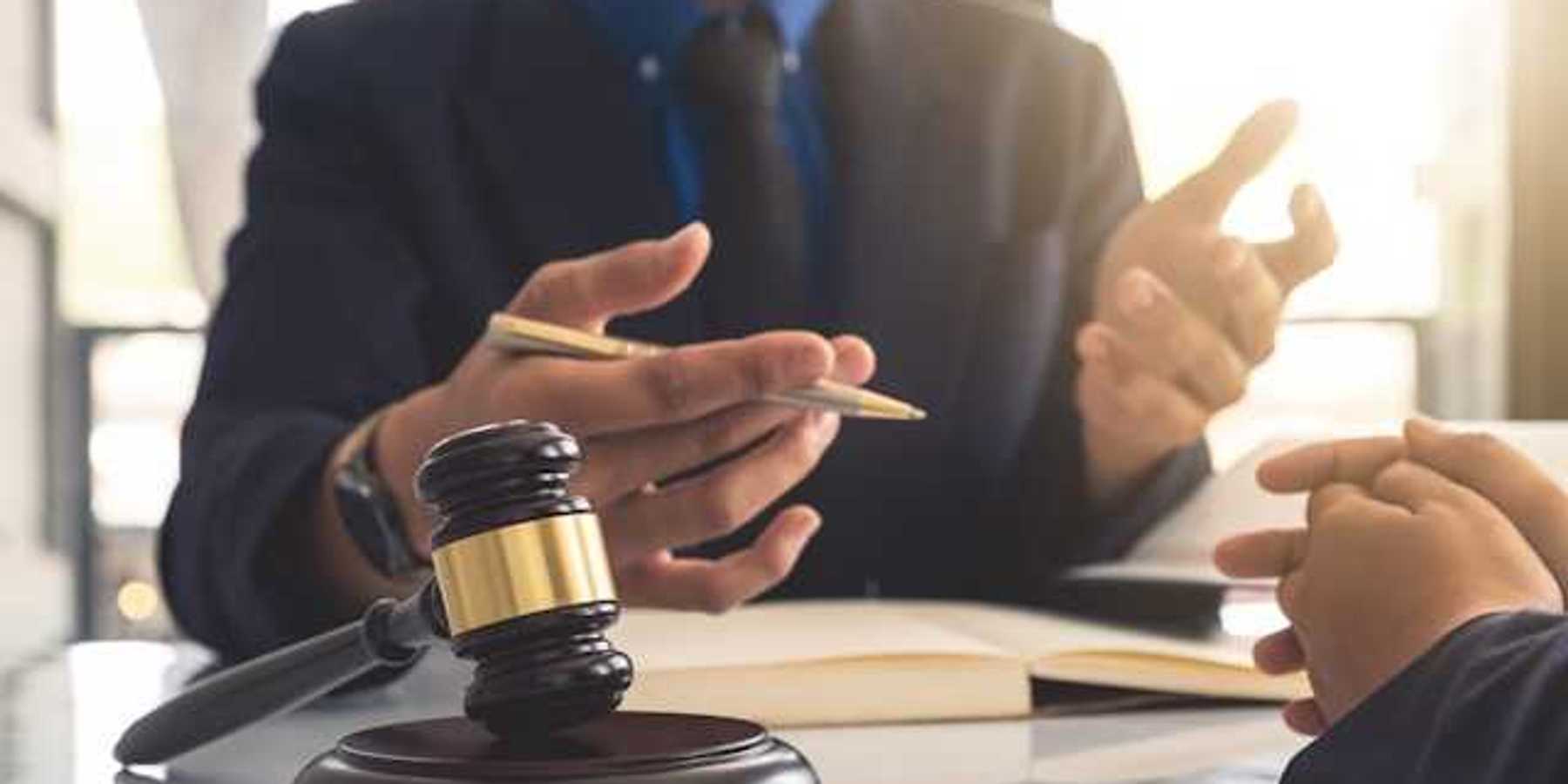 A person gesturing at another person with a court gavel in front of them