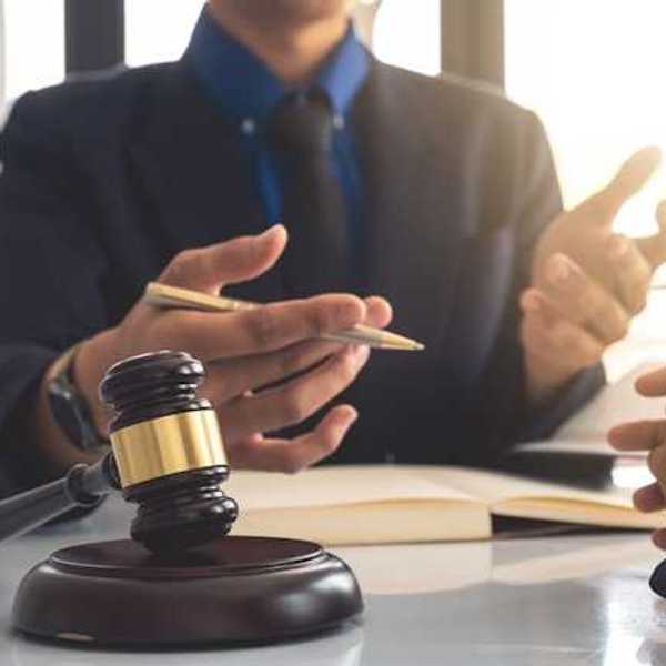 A person gesturing at another person with a court gavel in front of them