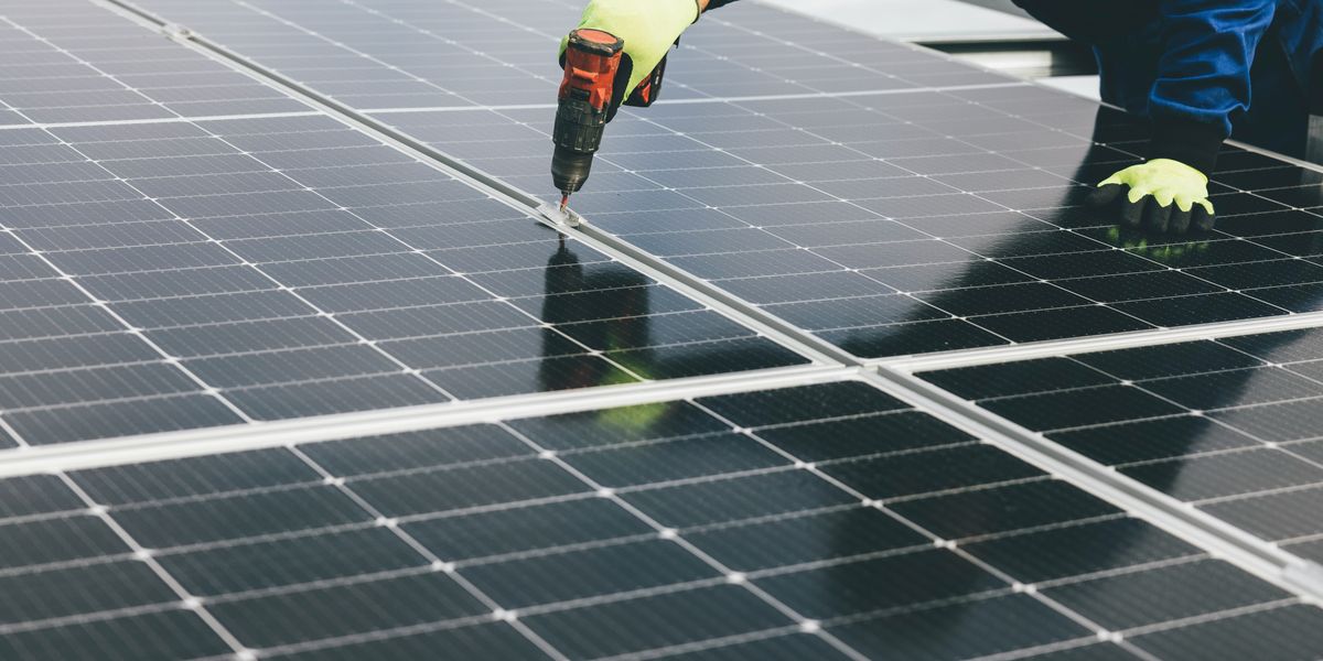 a person holding a a drill installing a solar panel.