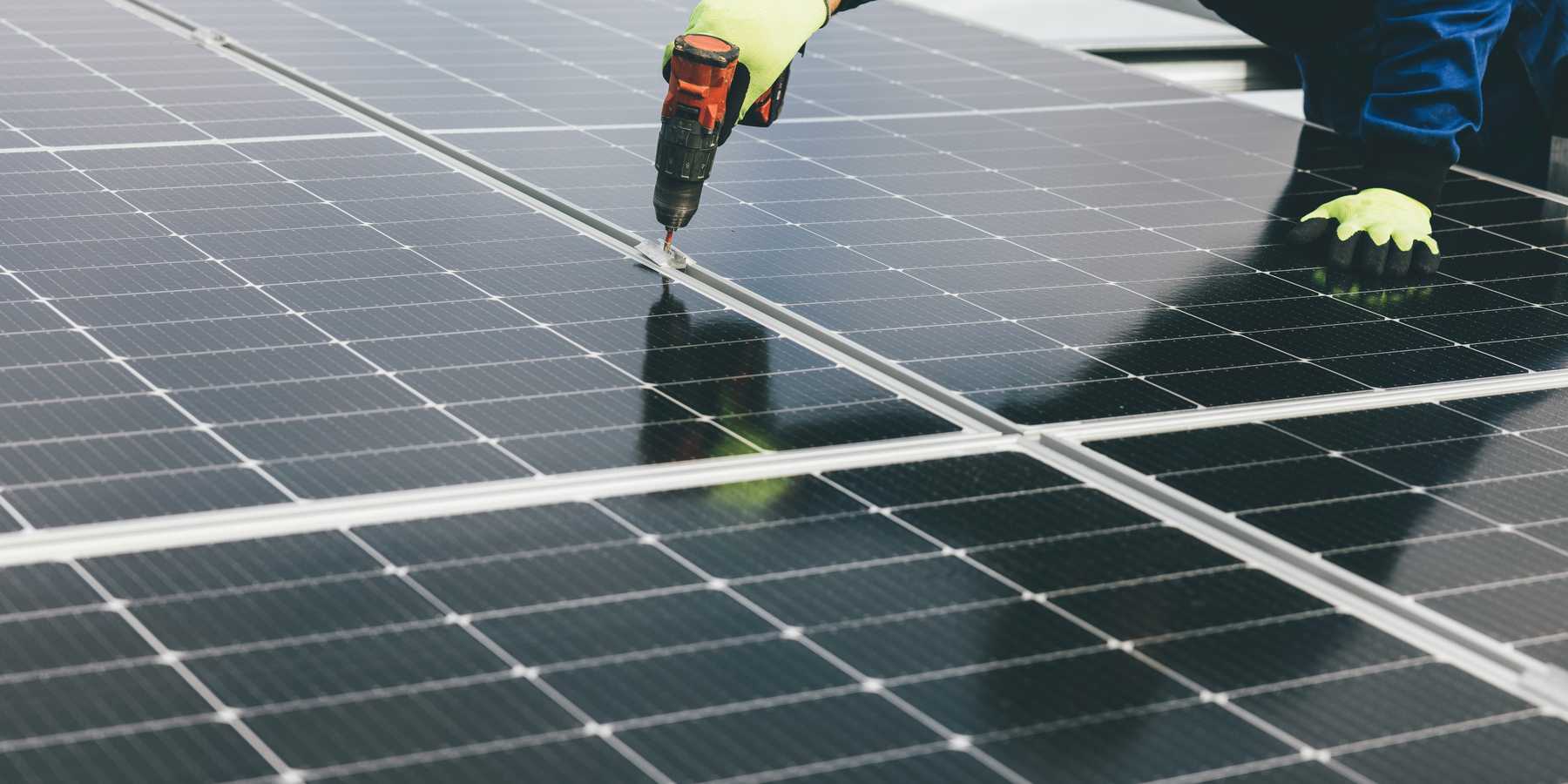 a person holding a a drill installing a solar panel.