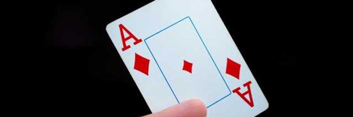 A person holding a card with the ace of diamonds on it