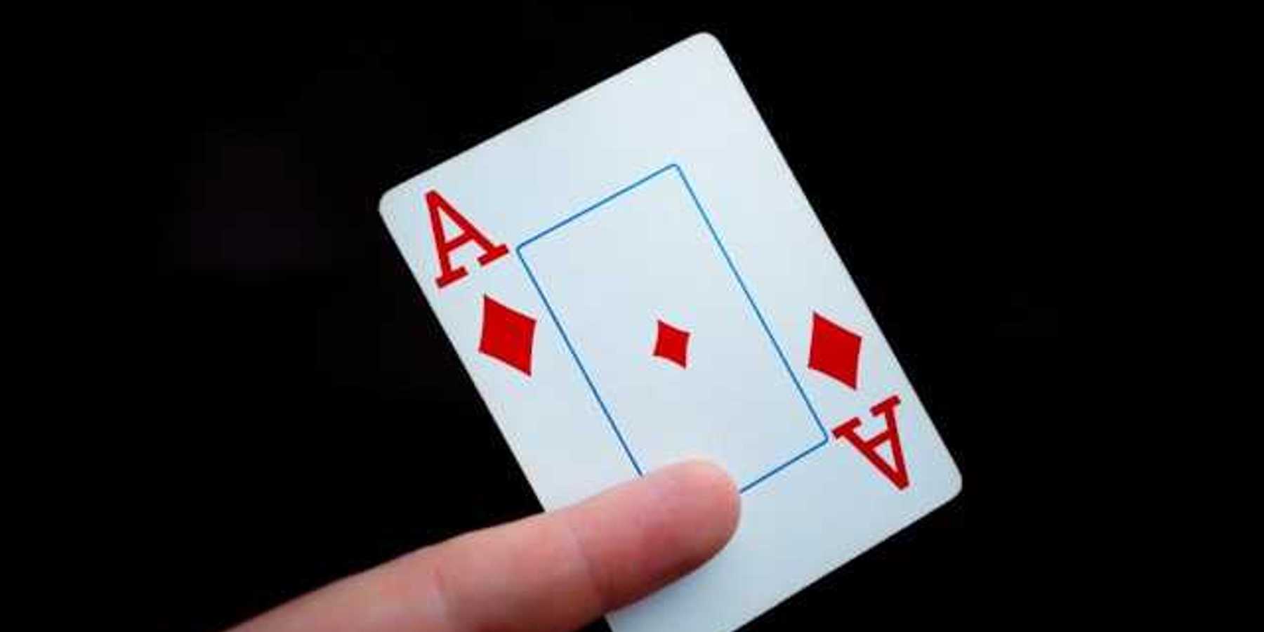 A person holding a card with the ace of diamonds on it