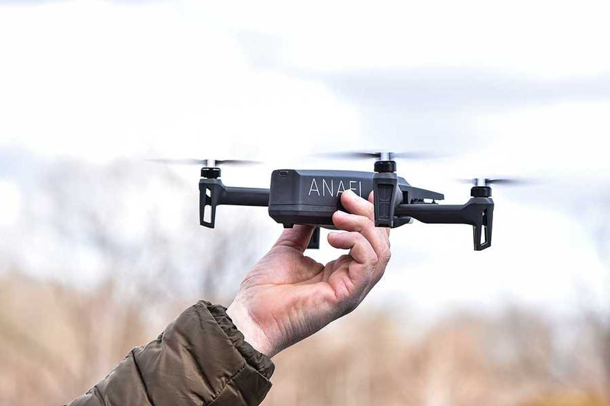 A person holding a drone aloft