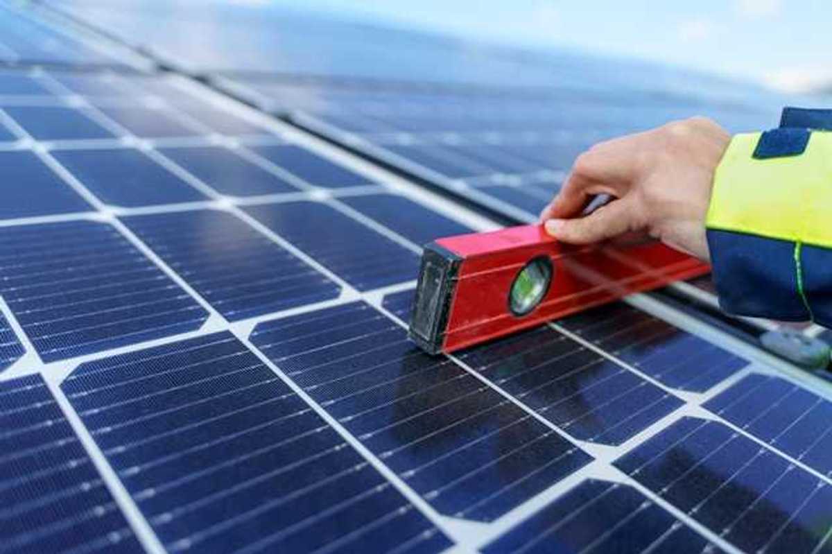 A person holding a level on a solar panel
