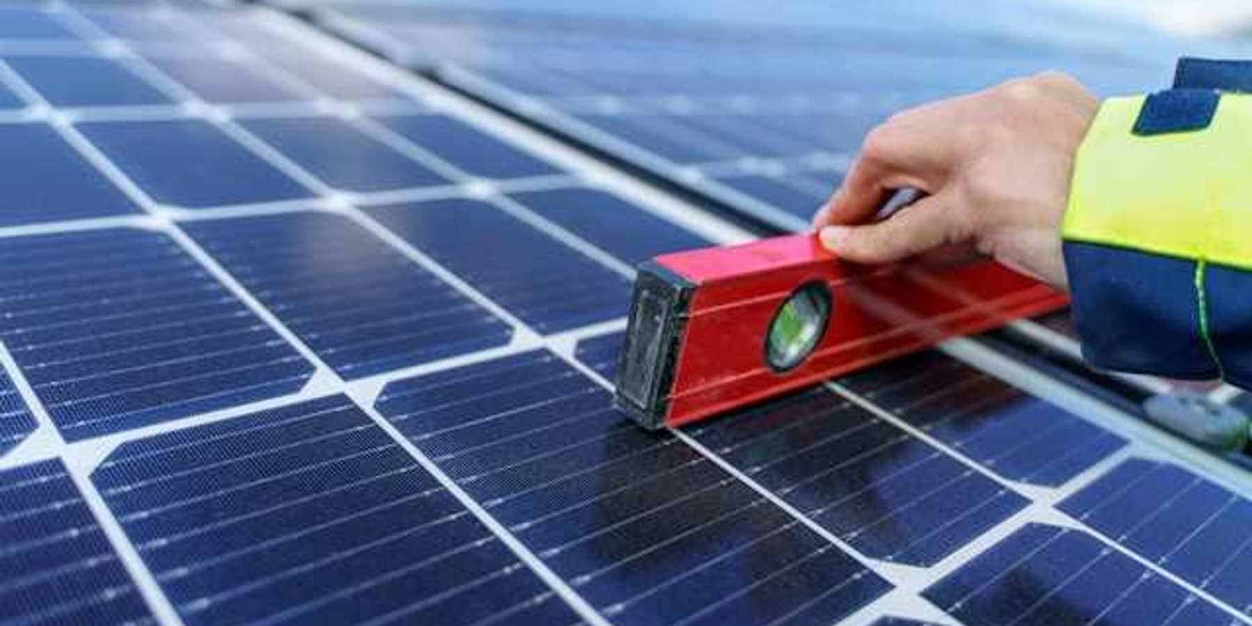A person holding a level on a solar panel