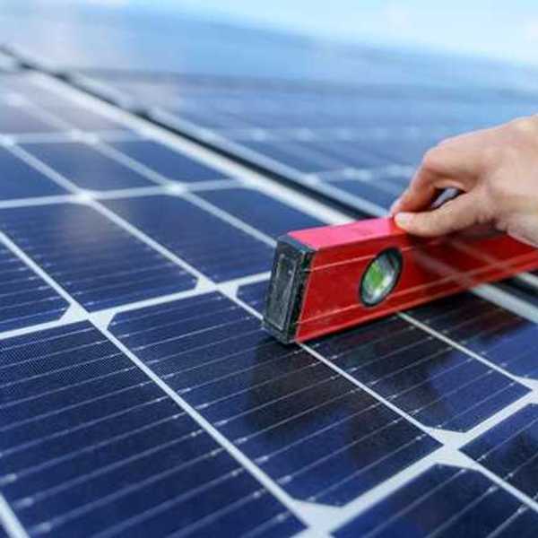 A person holding a level on a solar panel
