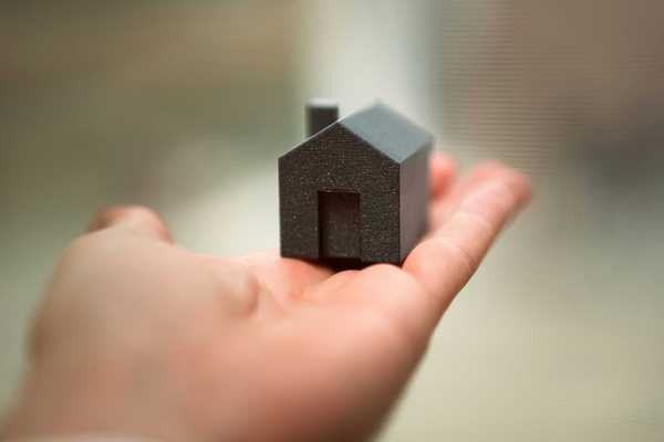 A person holding a small model of a house in their hand
