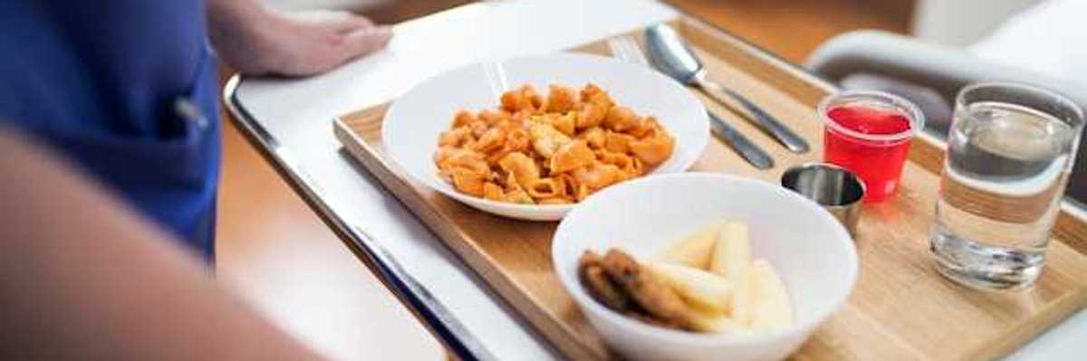 A person holding a tray with a hospital meal on it