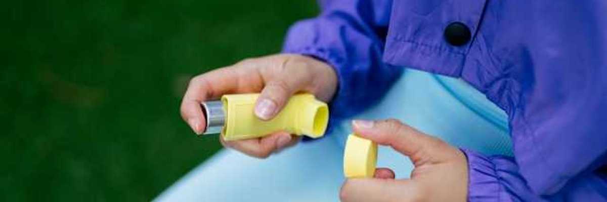 A person holding a yellow inhaler