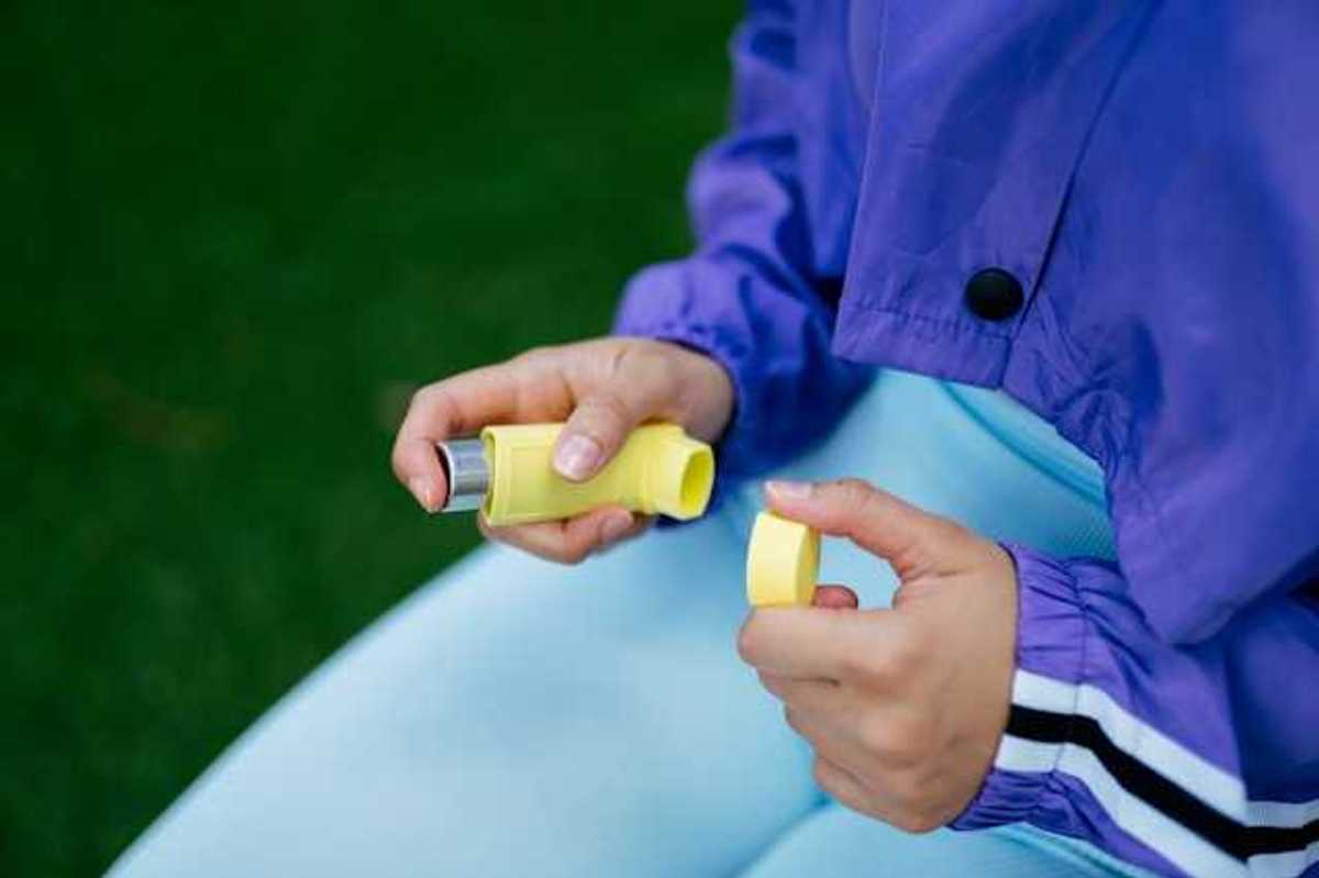 A person holding a yellow inhaler