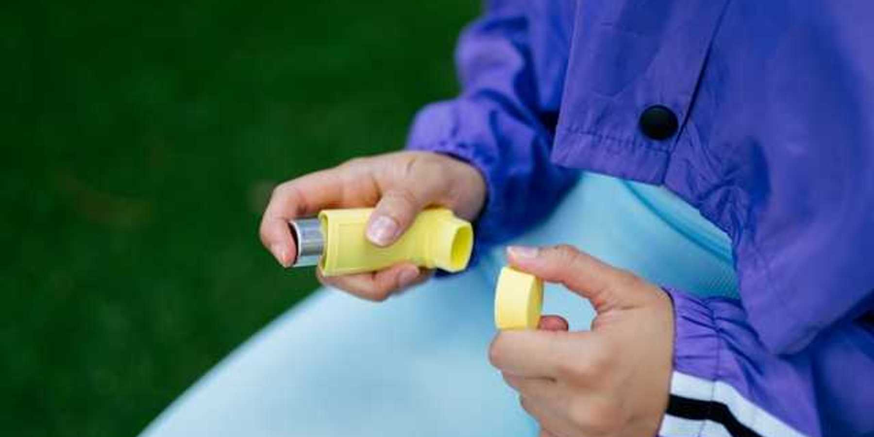 A person holding a yellow inhaler