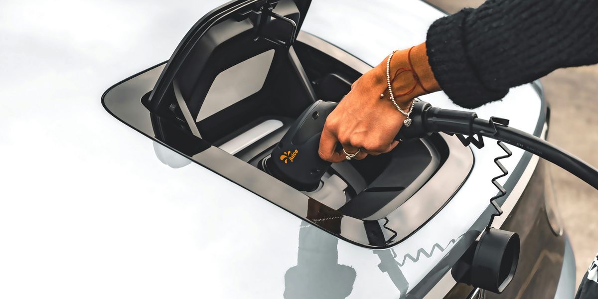A person inserting a charger into an electric vehicle.