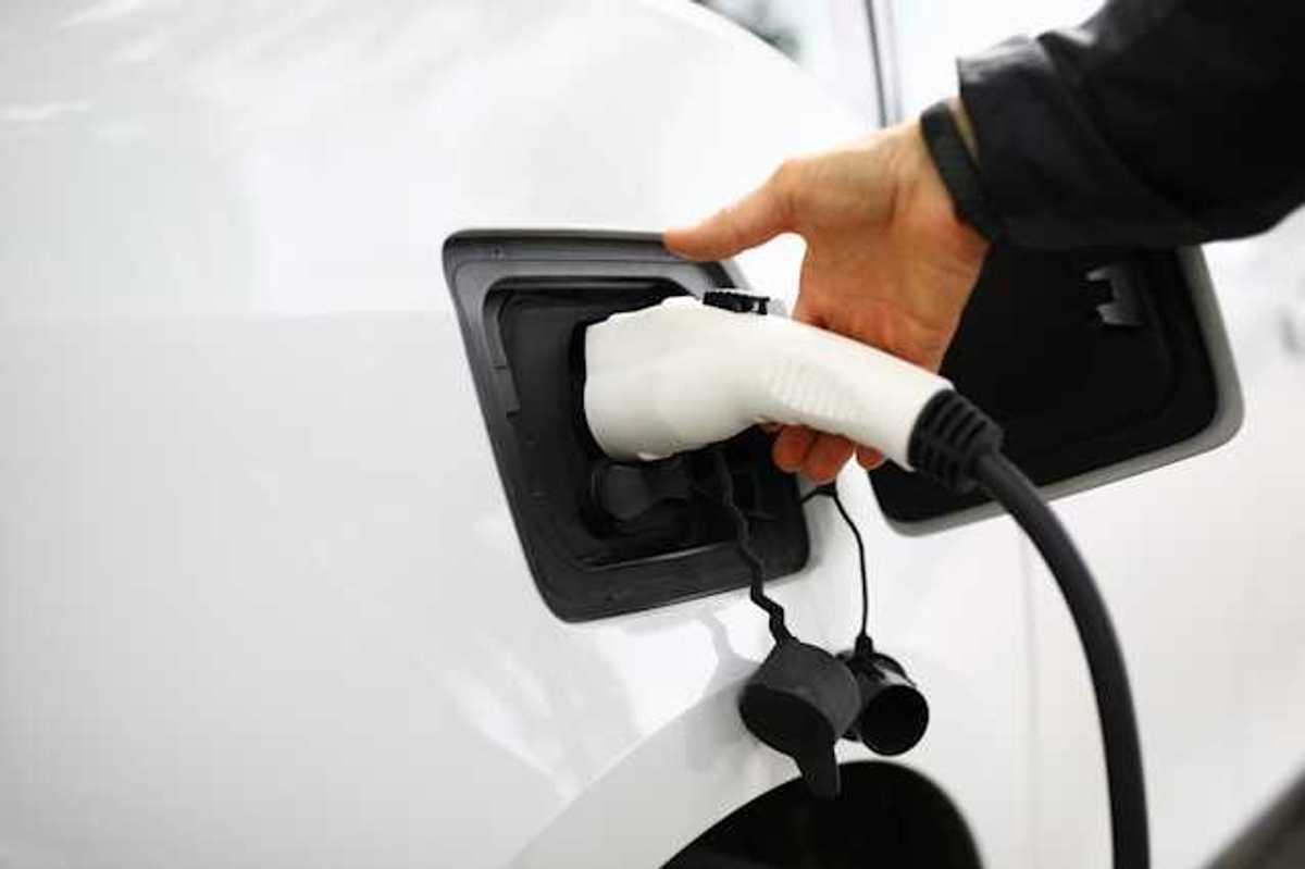 A person inserting a charger into an electric vehicle
