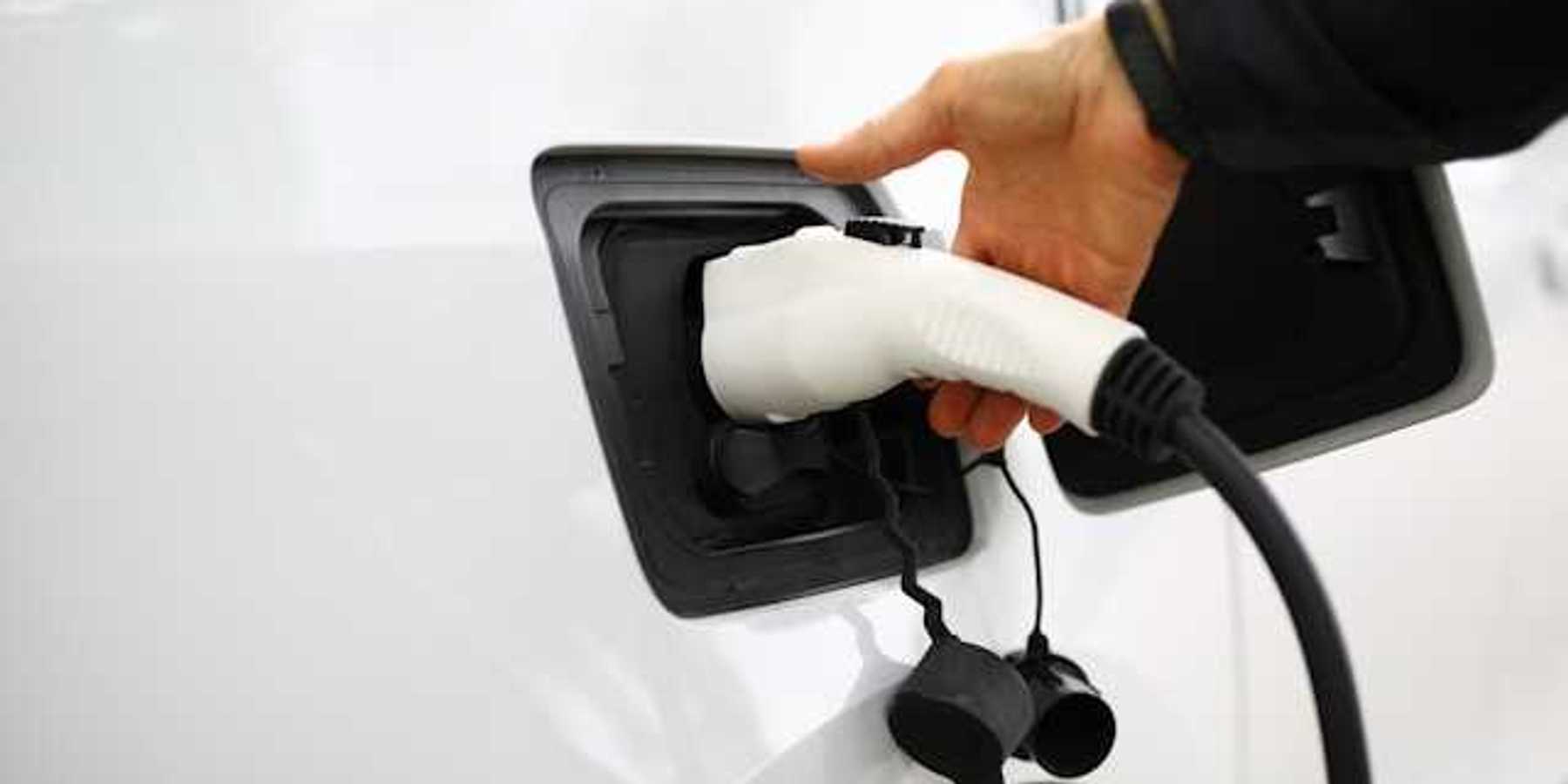A person inserting a charger into an electric vehicle
