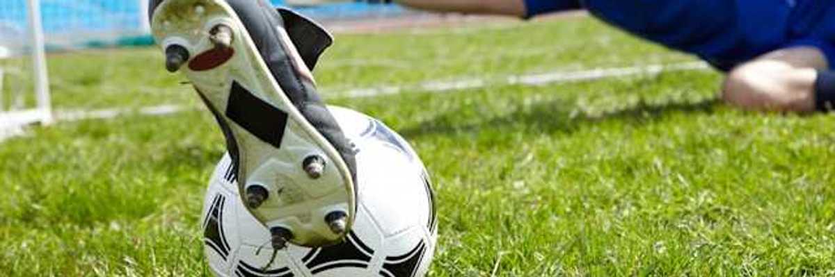 A person kicking a soccer ball into a goal