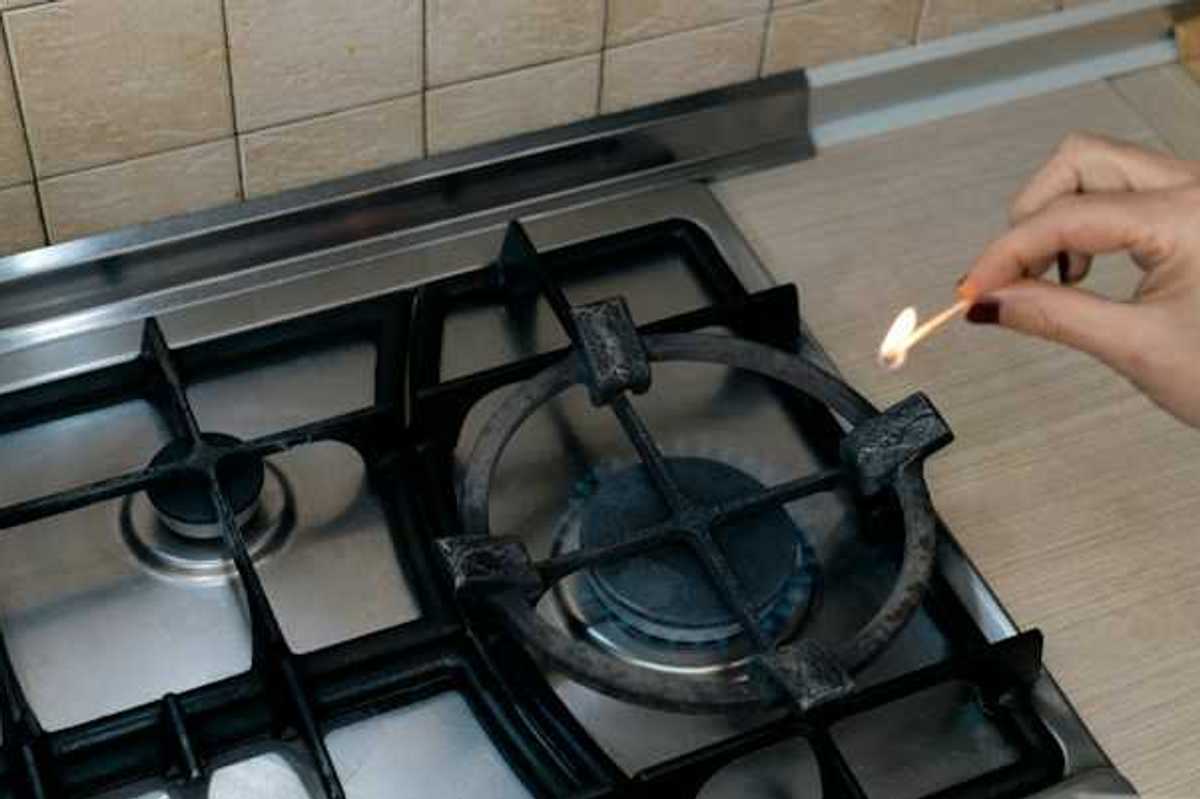 A person lighting a match on a gas stove