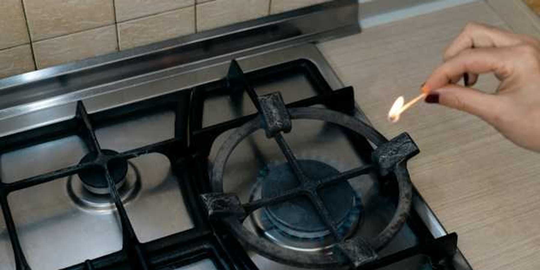A person lighting a match on a gas stove