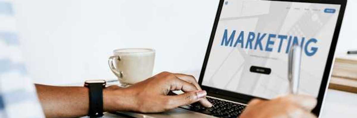 A person looking at a laptop with the word Marketing on the screen