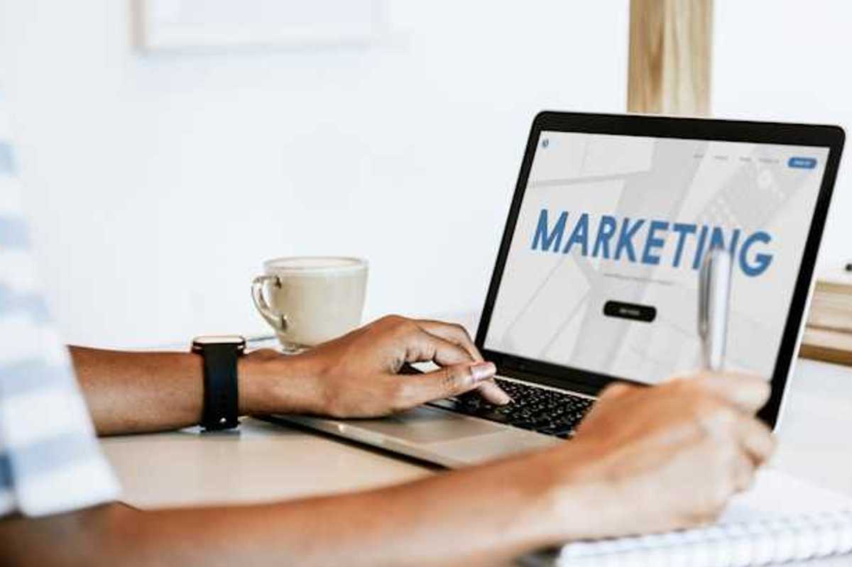 A person looking at a laptop with the word Marketing on the screen