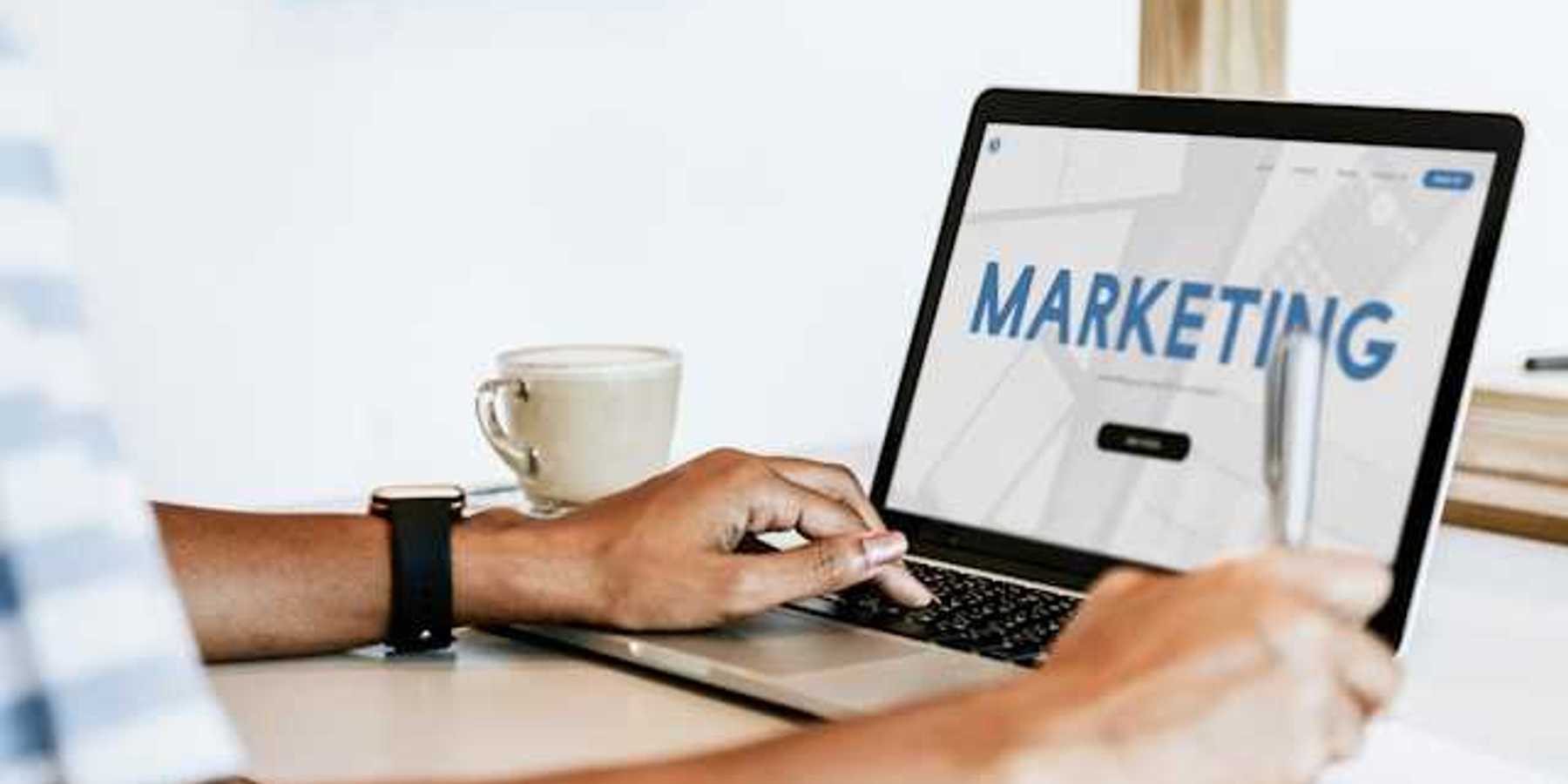 A person looking at a laptop with the word Marketing on the screen