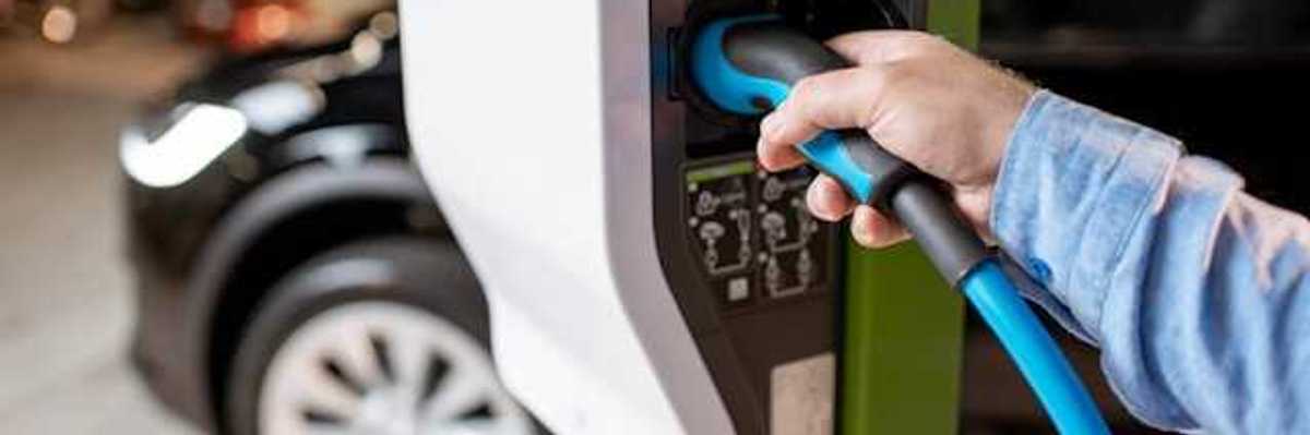 A person plugging an EV into a car charger