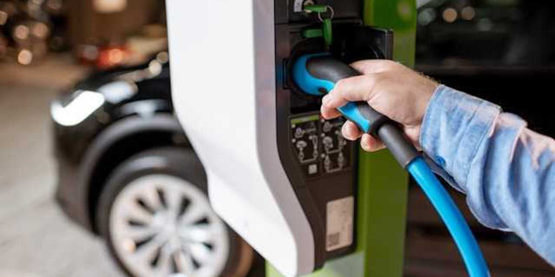 A person plugging an EV into a car charger