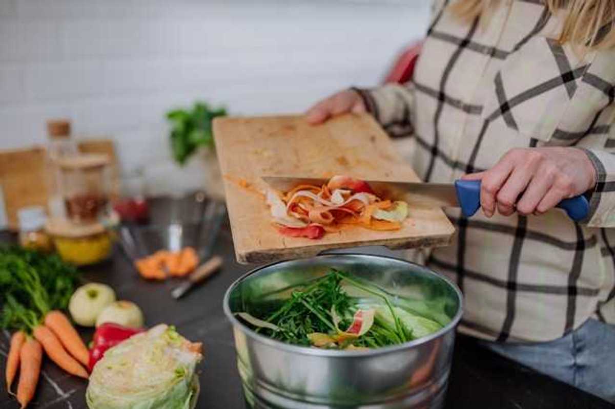 A person putting food into a composting container while cooking