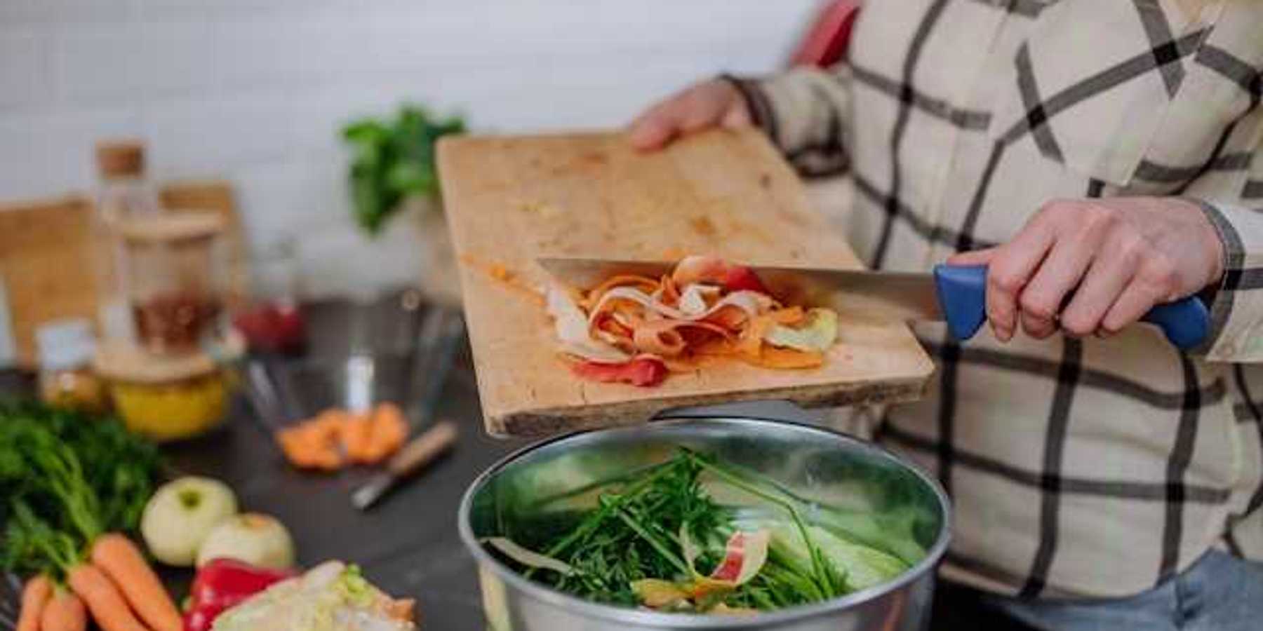 A person putting food into a composting container while cooking