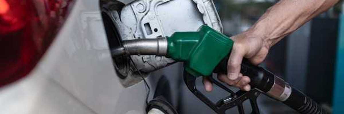 A person's hand holding a gas pump while pumping gas into car