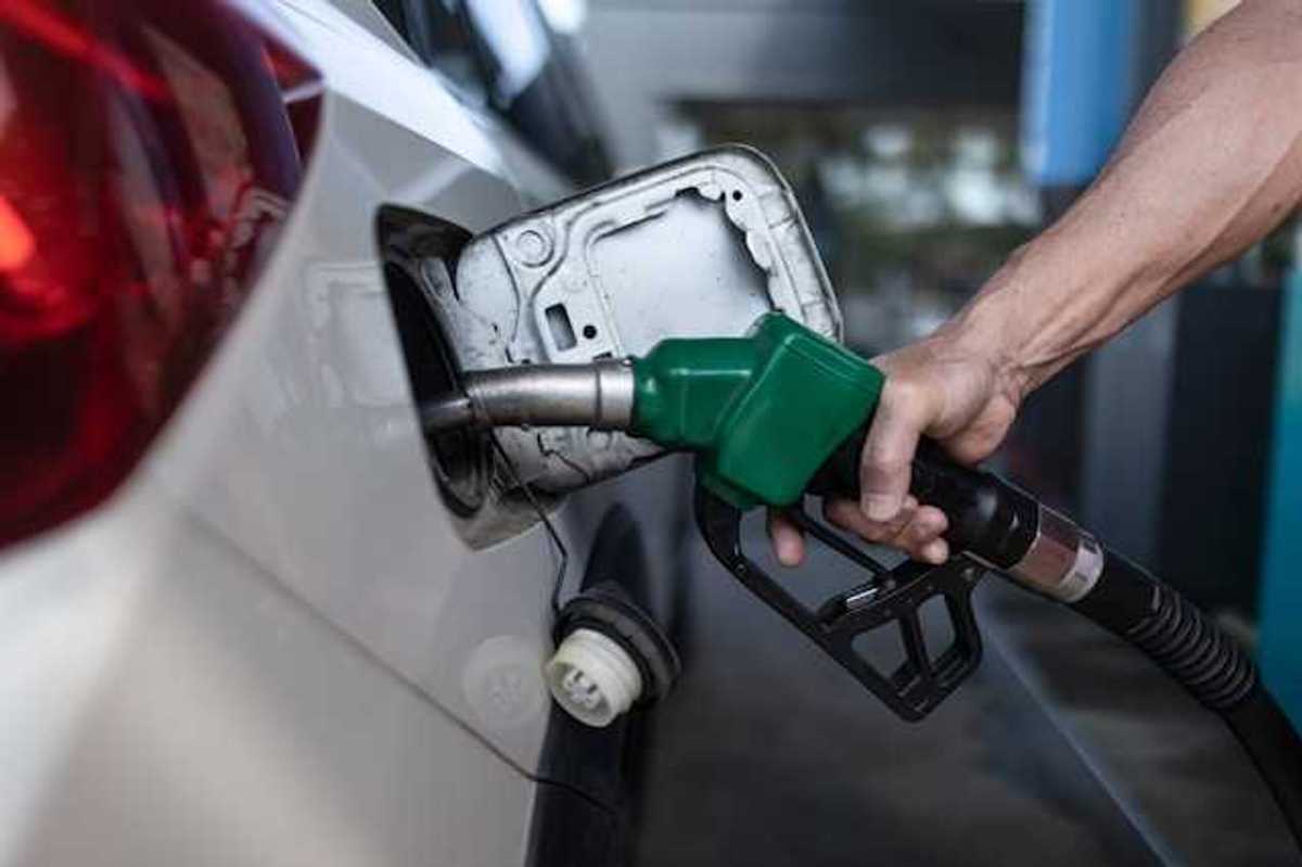 A person's hand holding a gas pump while pumping gas into car