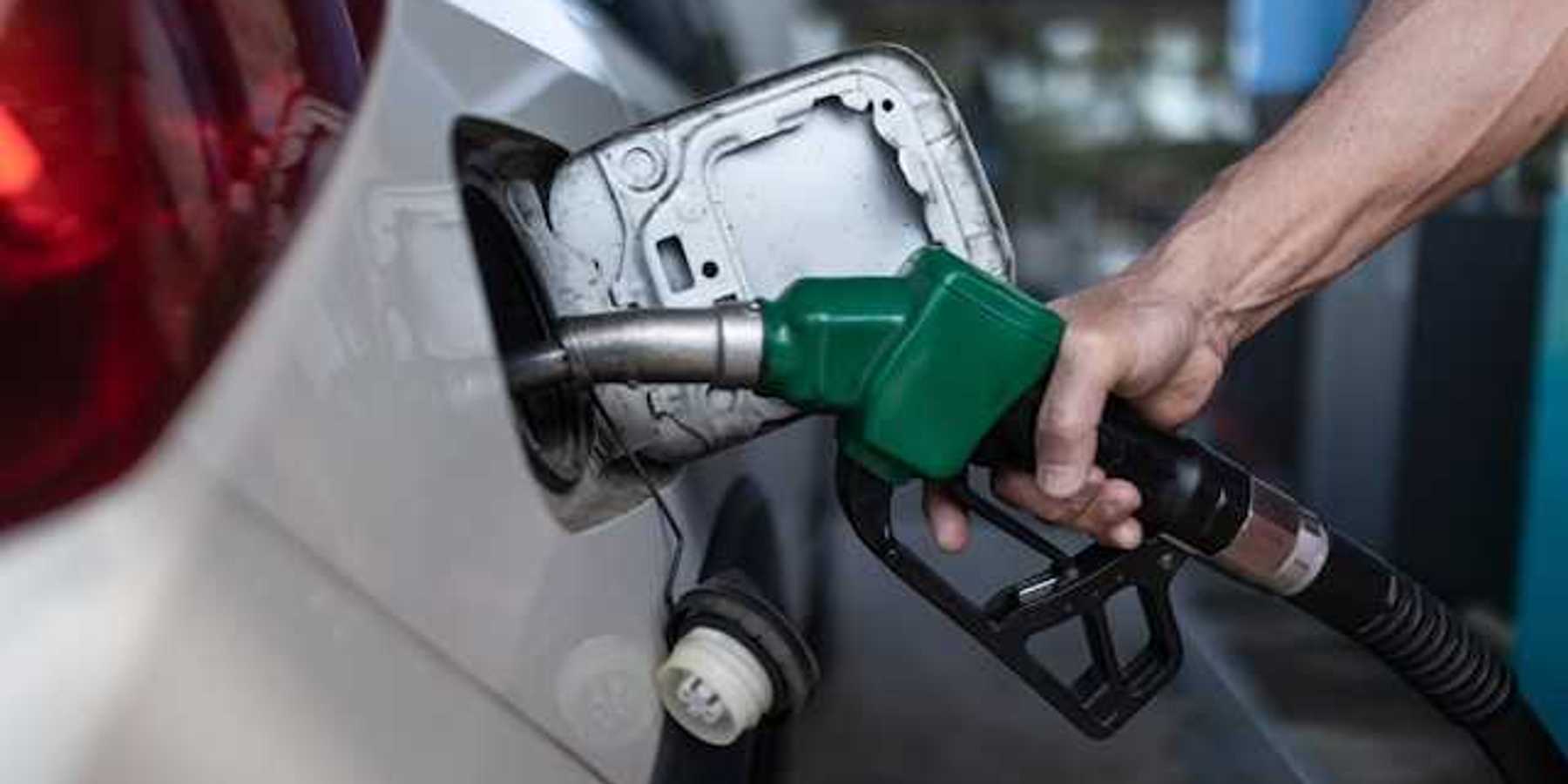 A person's hand holding a gas pump while pumping gas into car