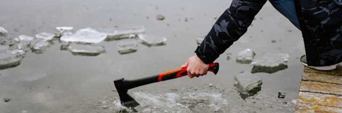 A person sitting on a dock breaking the ice on a lake