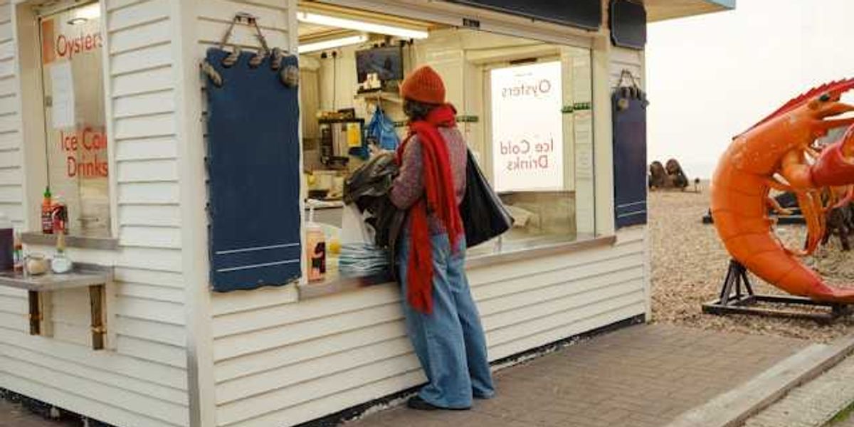 A person standing at an outdoor kiosk which sells oysters