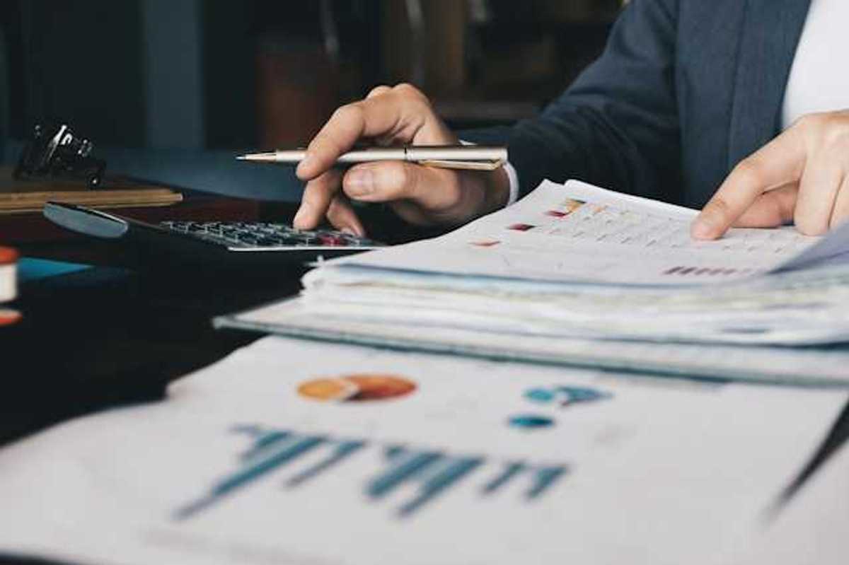 A person using a calculator to verify numbers on a financial document