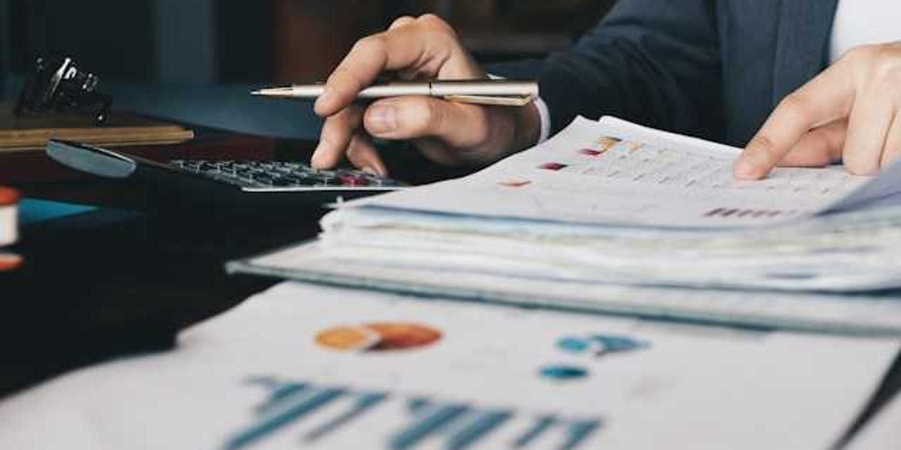 A person using a calculator to verify numbers on a financial document