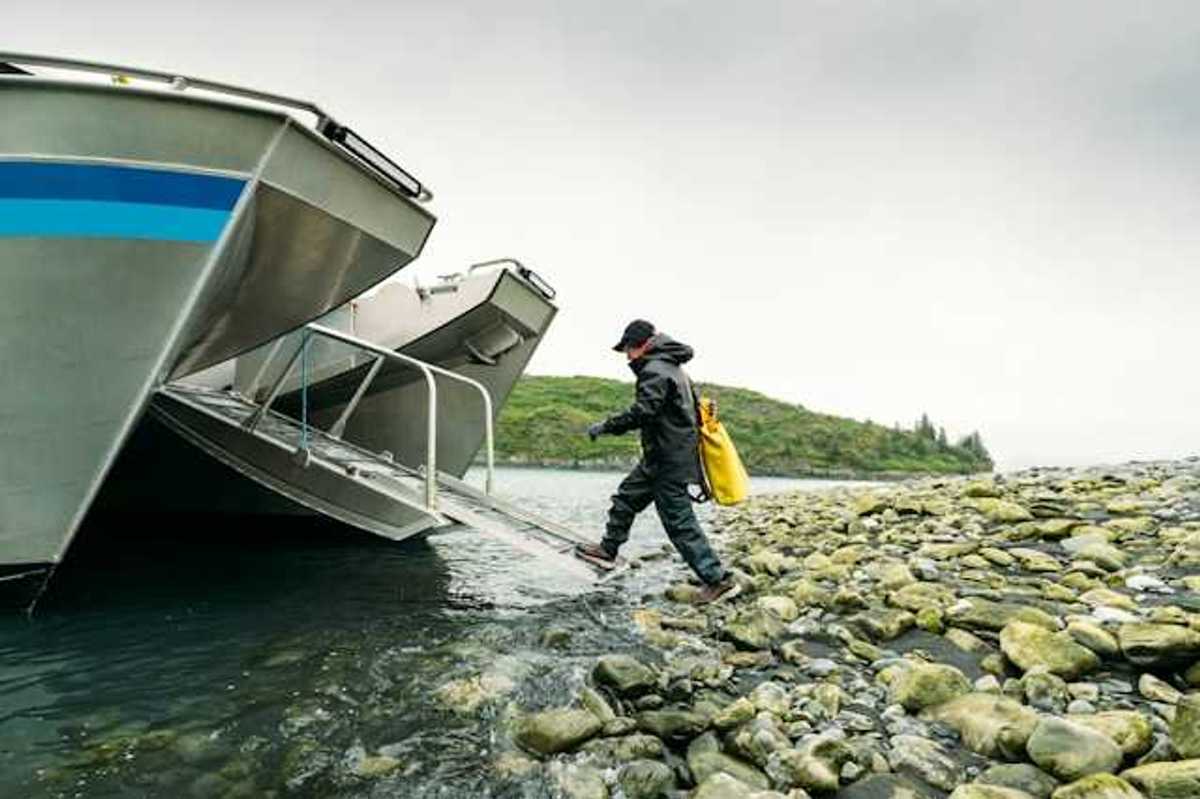 A person walking into a boat ramp off a rocky shore in the wilderness