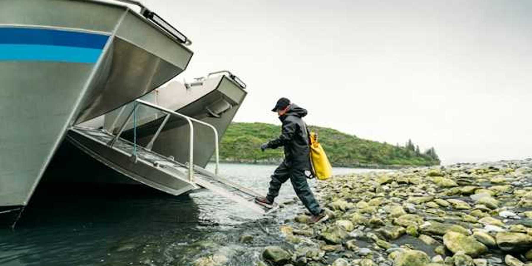 A person walking into a boat ramp off a rocky shore in the wilderness