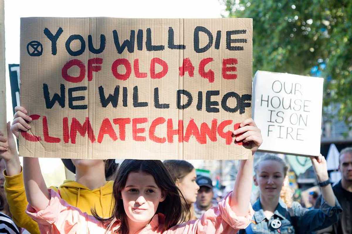 A person with a sign saying 'You will die of old age; we will die of climate change'