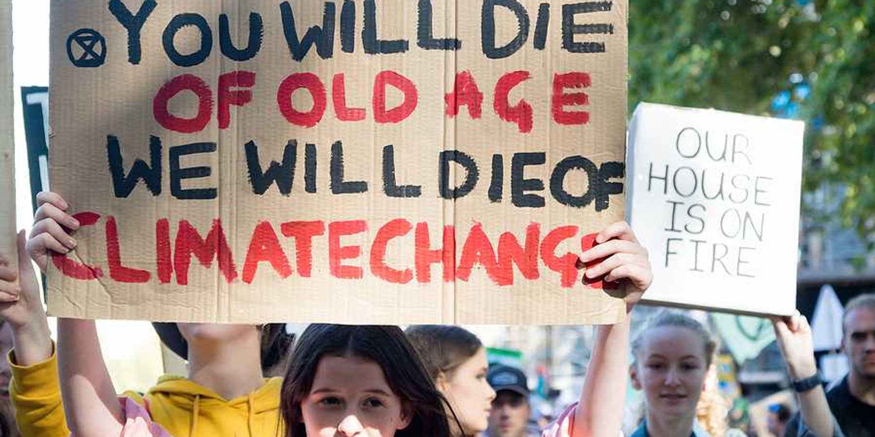 A person with a sign saying 'You will die of old age; we will die of climate change'
