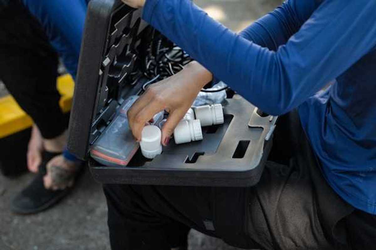 A person with a small case on their lap with water testing tools