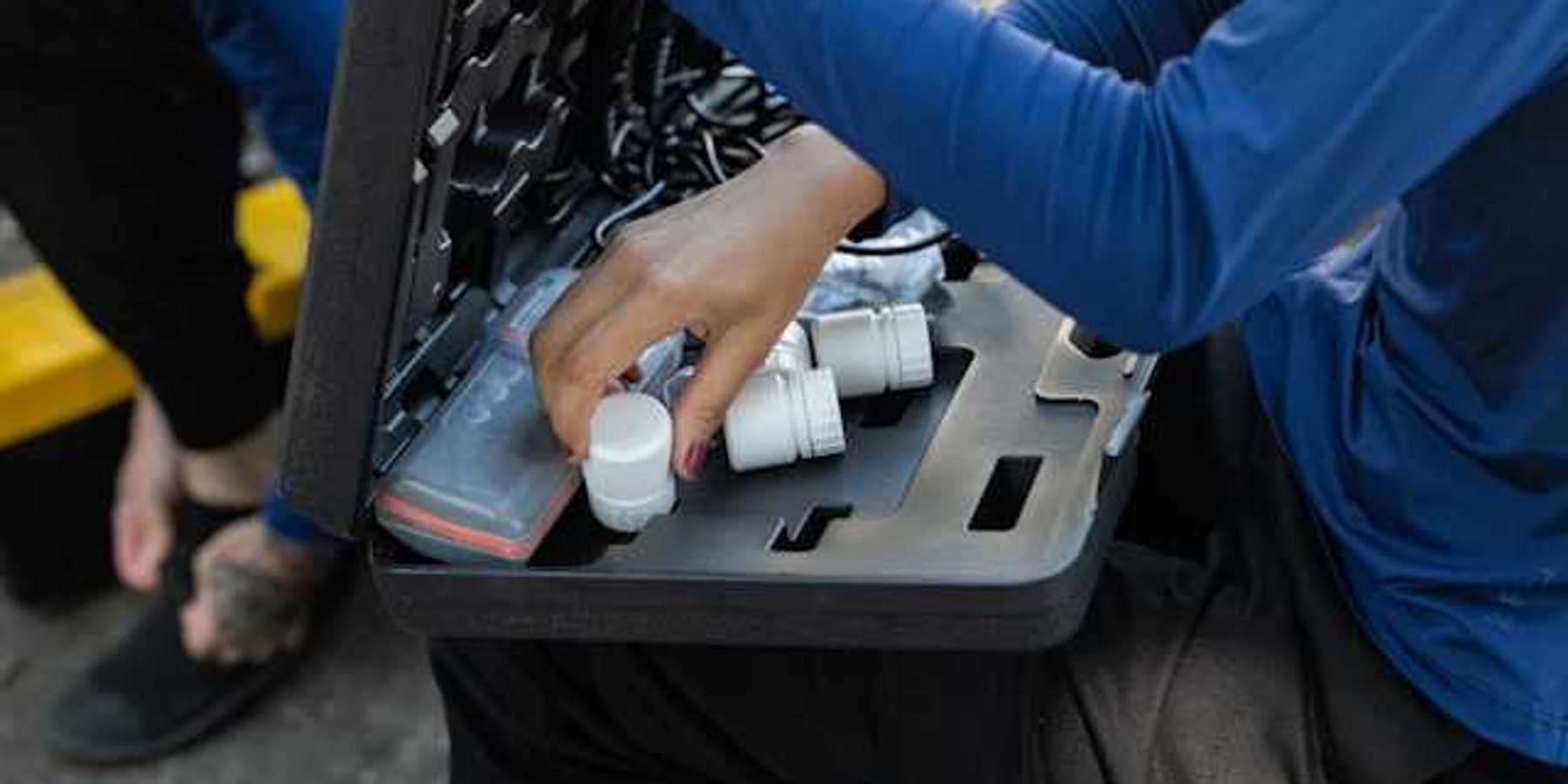A person with a small case on their lap with water testing tools