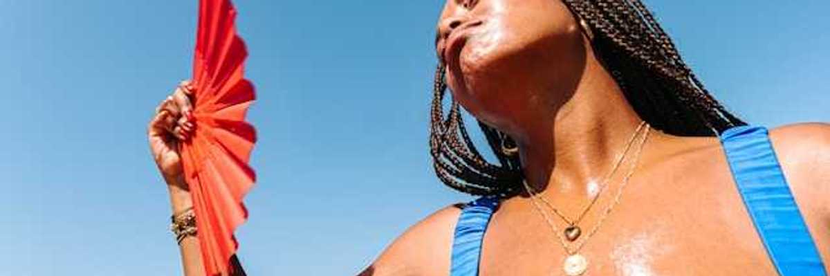 A perspiring woman fanning herself on a sunny day