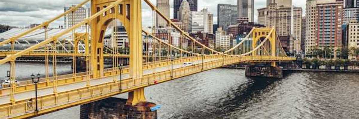A photo of a yellow bridge crossing the river into downtown Pittsburgh