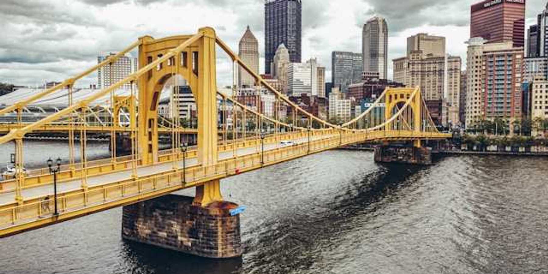 A photo of a yellow bridge crossing the river into downtown Pittsburgh